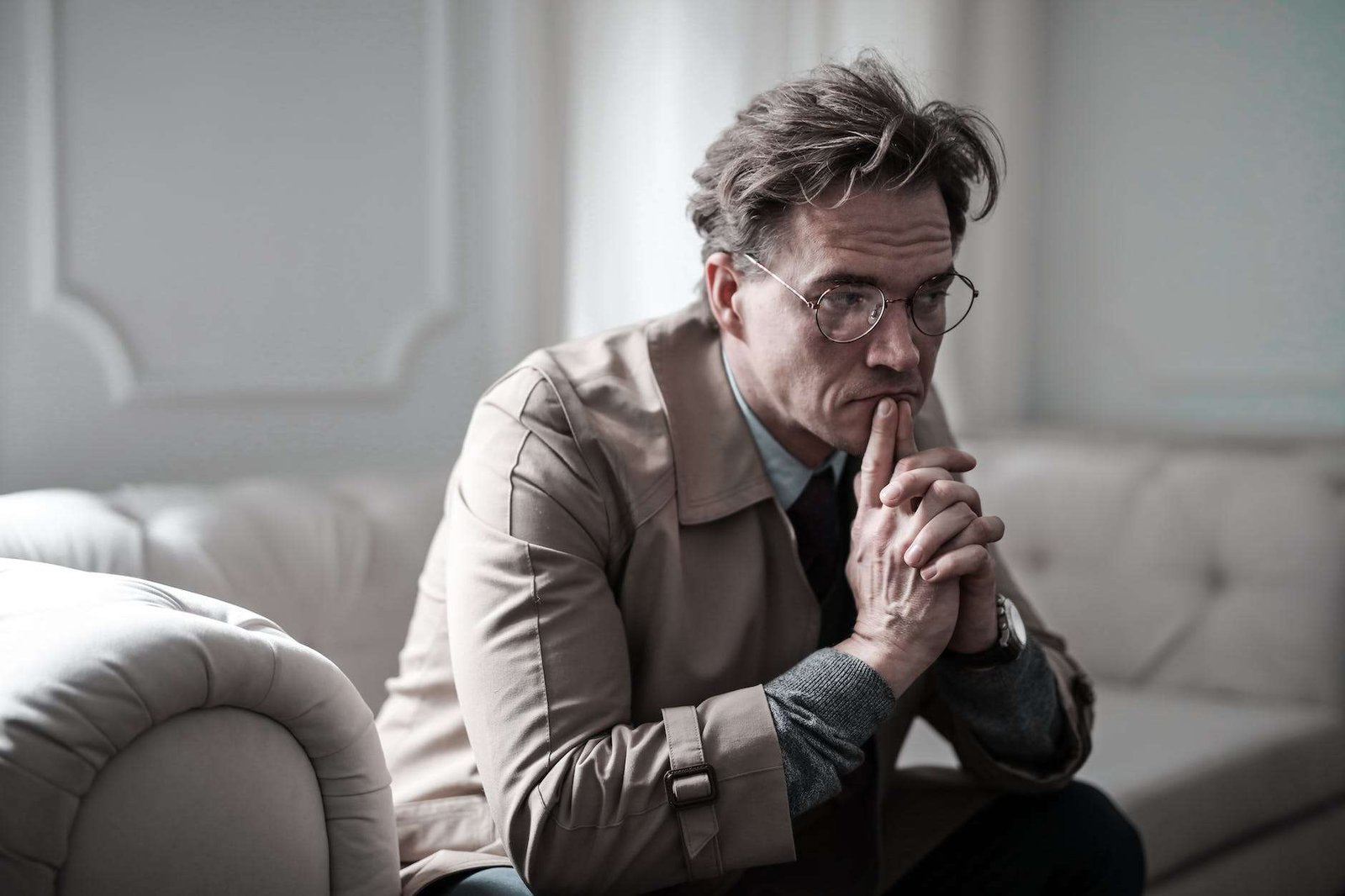 man in brown suit jacket sitting on white sofa