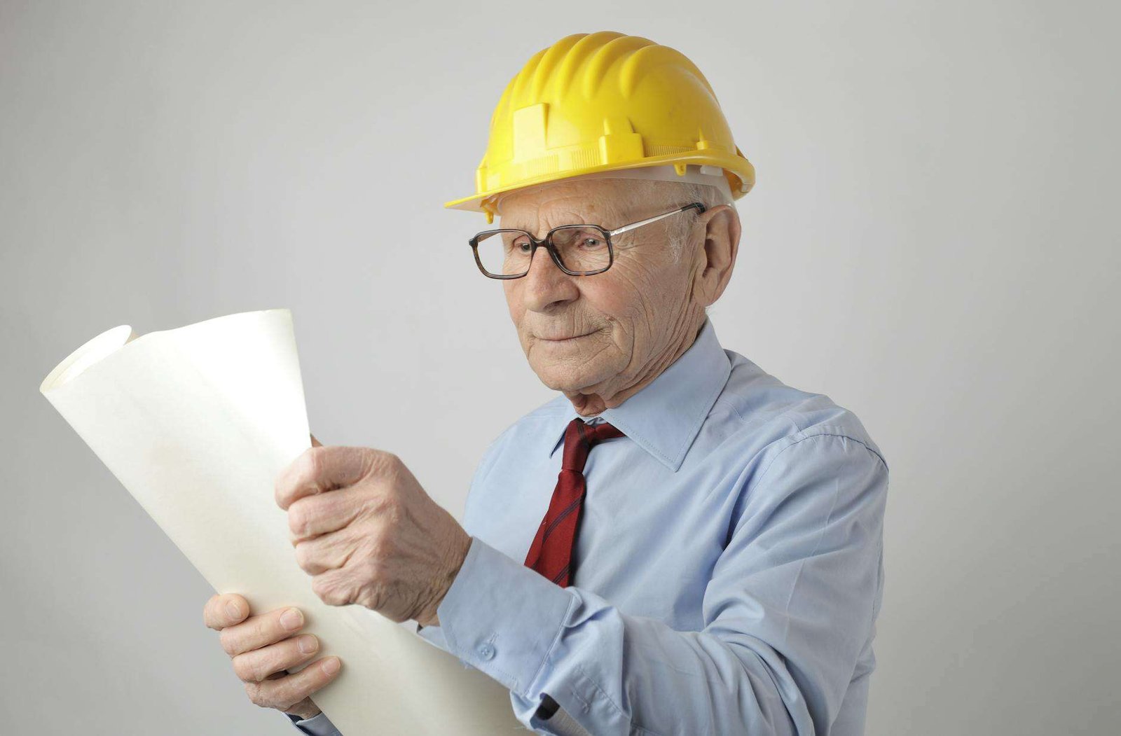 senior male engineer reading blueprint in studio