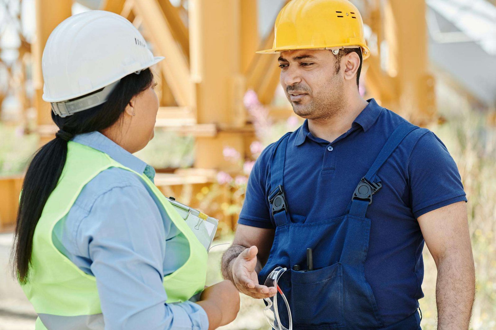 a man in blue shirt talking to the woman wearing safety vest