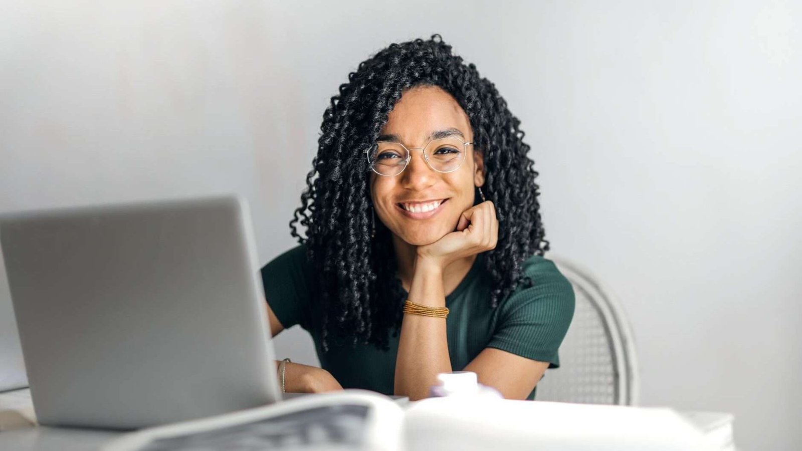 happy ethnic woman sitting at table with laptop