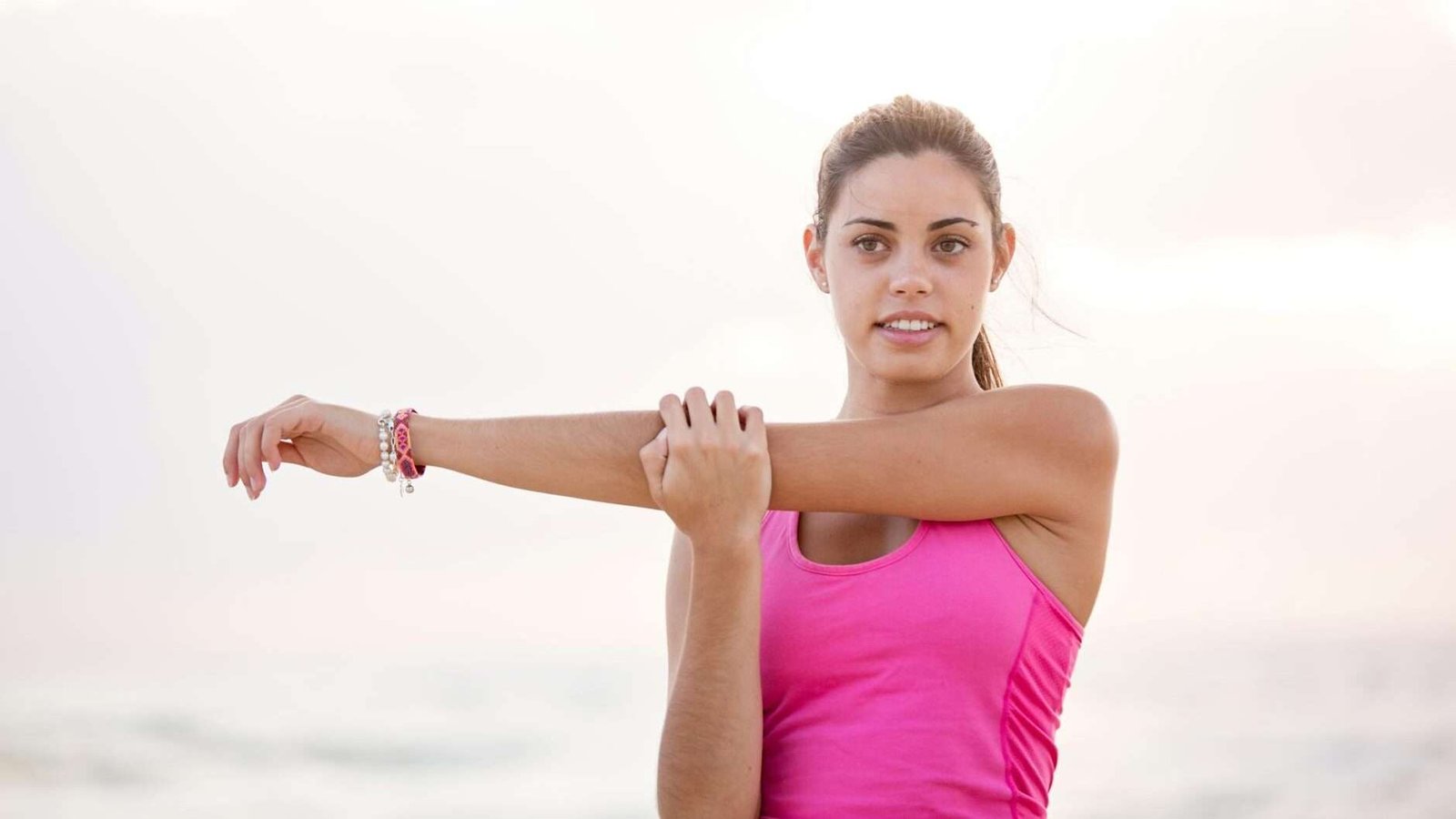 photography of woman in pink tank top stretching arm