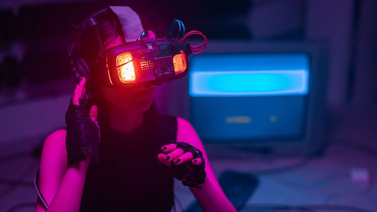 woman wearing illuminated goggles in a room with computer and cables in the background