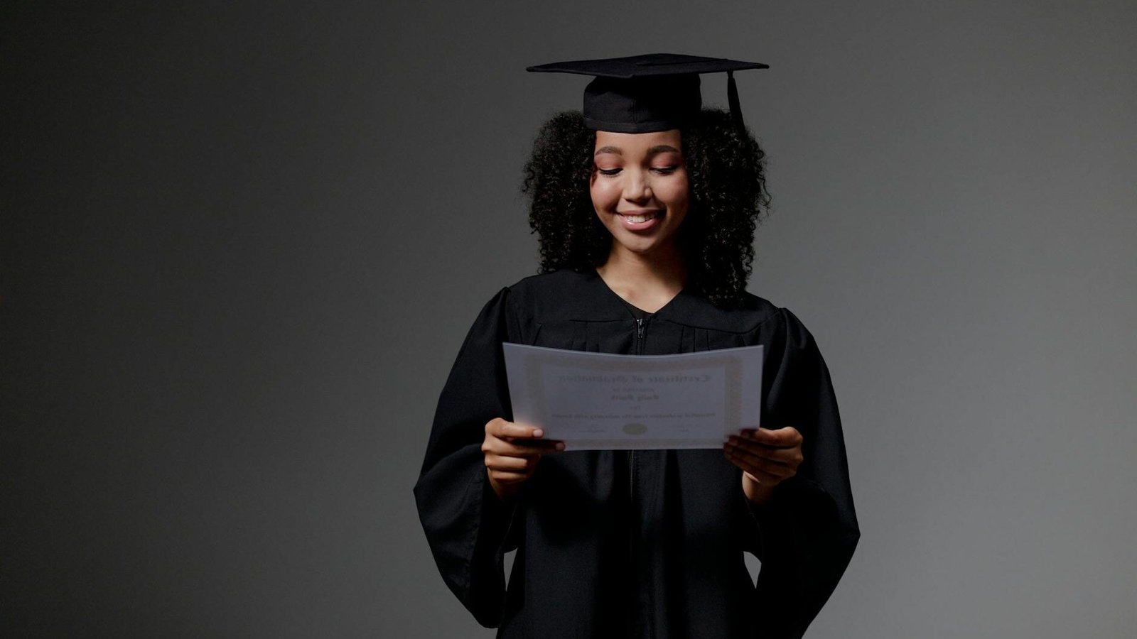 curly haired graduate student holding certificate