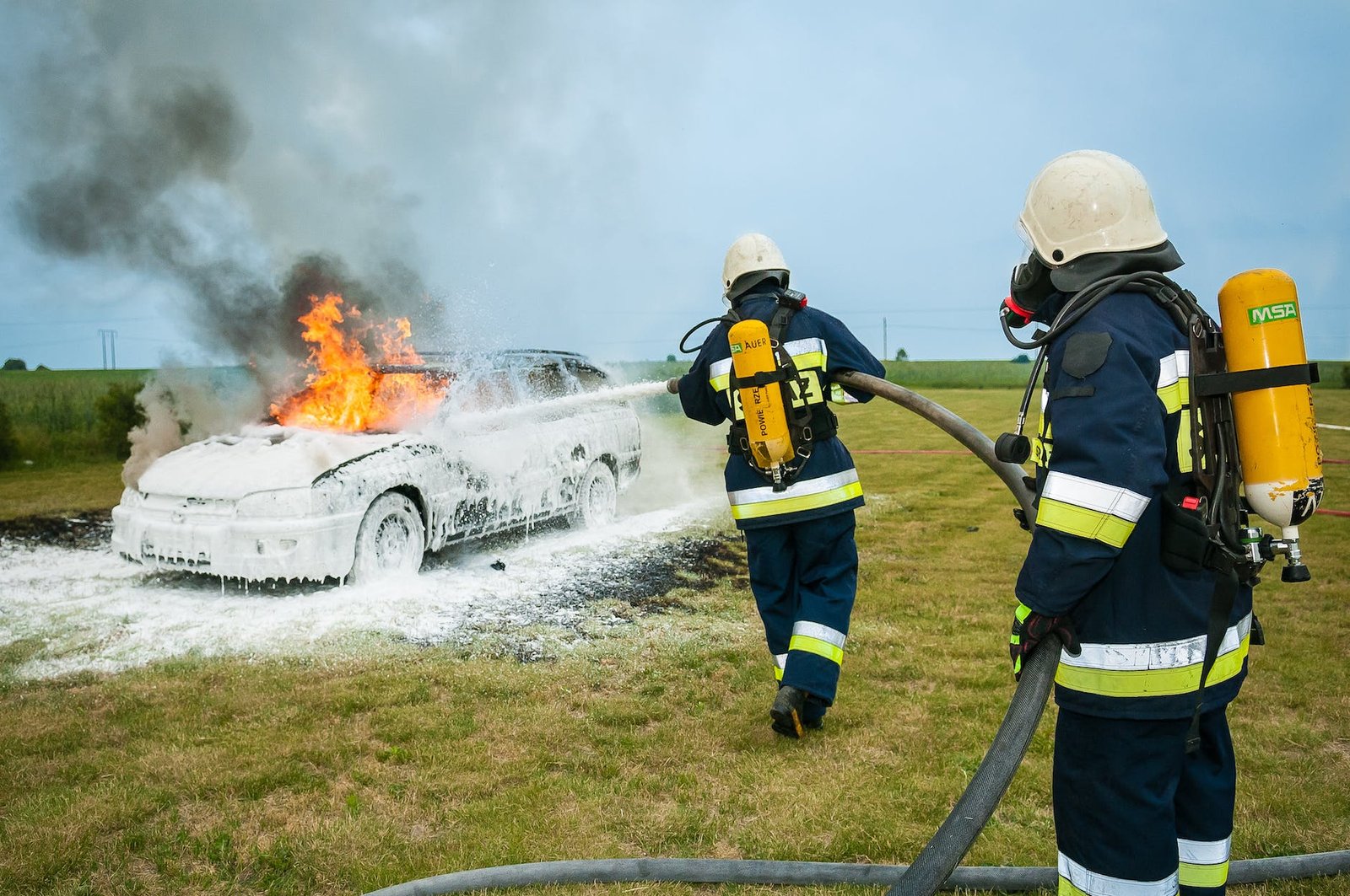 firemen spraying on flaming vehicle