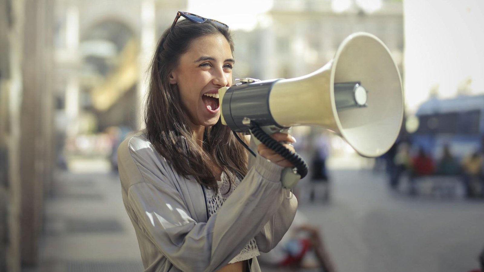 cheerful young woman screaming into megaphone