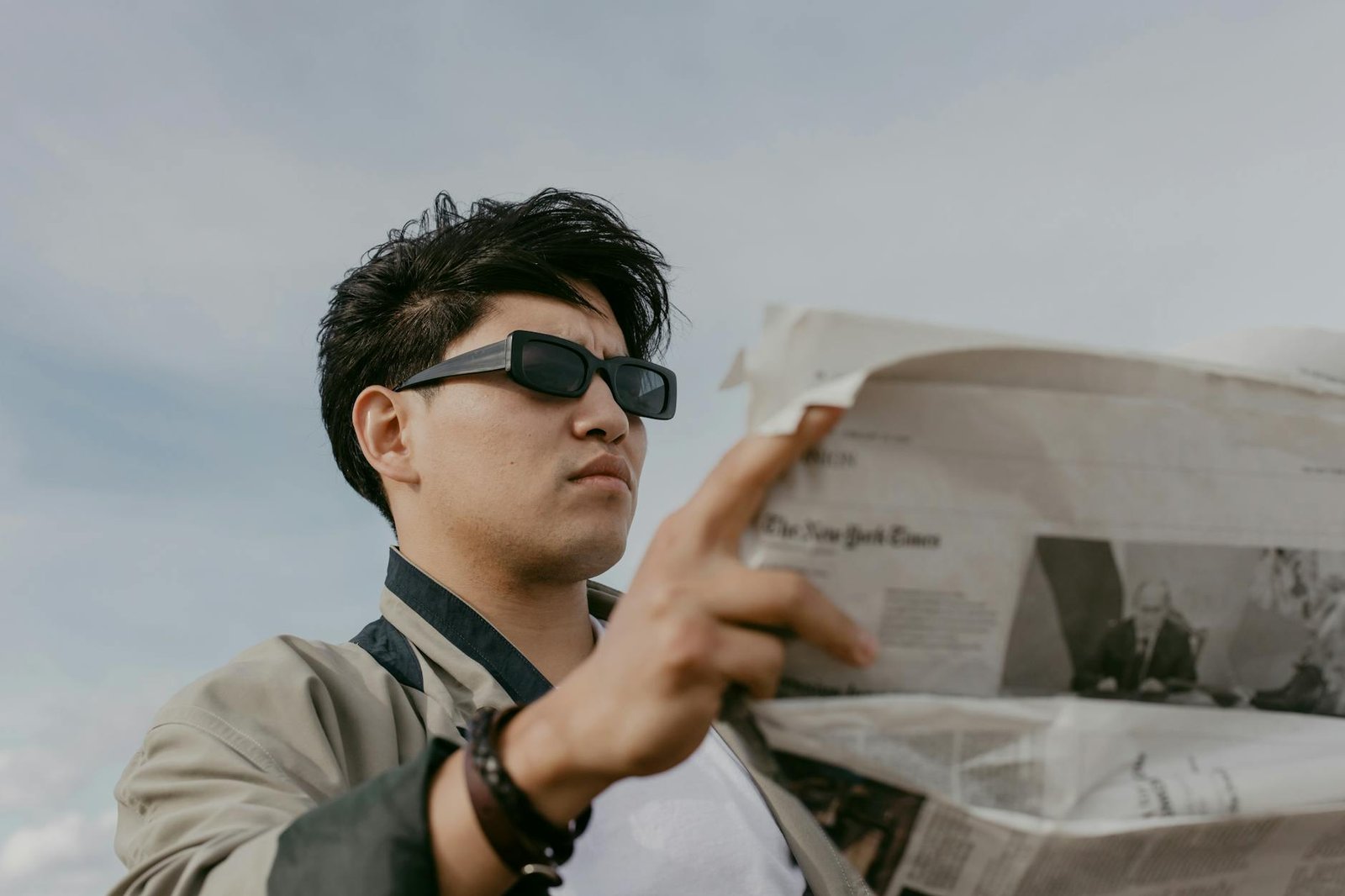 man in gray jacket holding newspaper